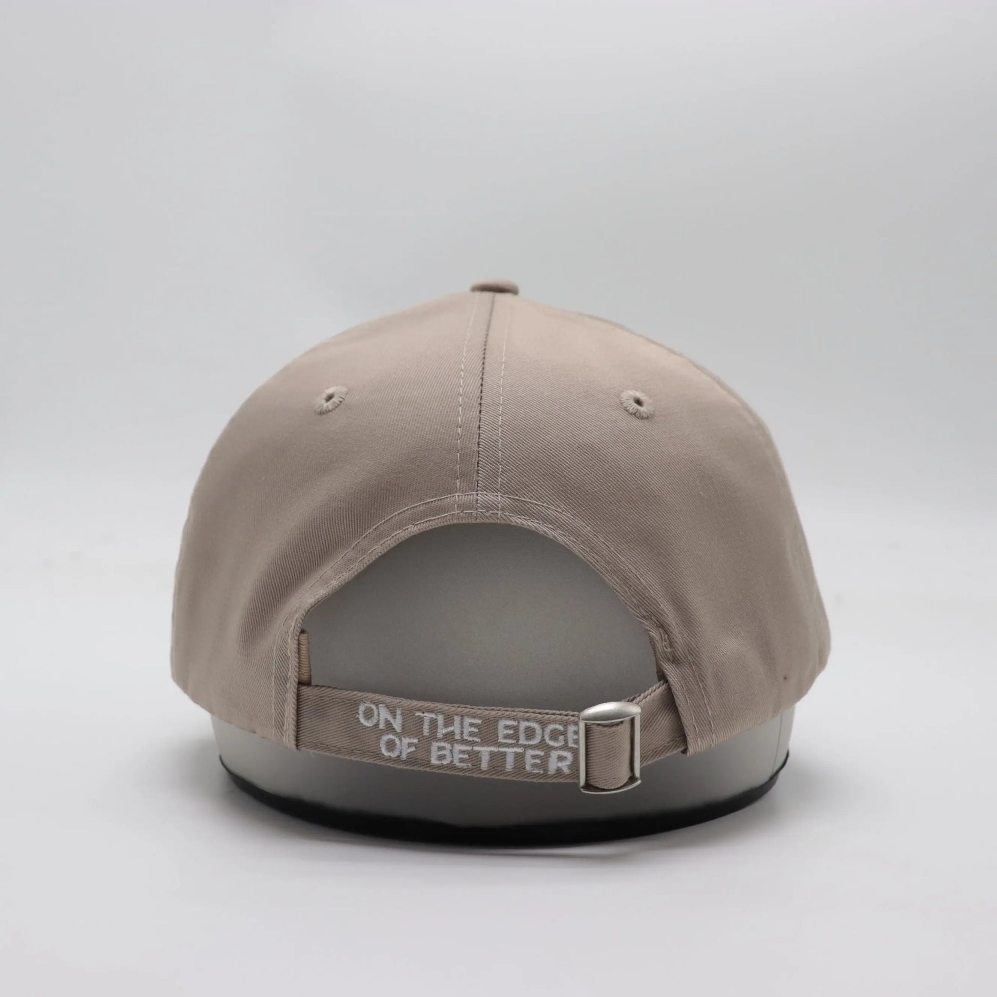 Backside view of The TideTurner hat in ivory color made of 65% recycled ocean bound plastic featuring embroidered Liminal Life's slogan  "On The Edge Of Better".