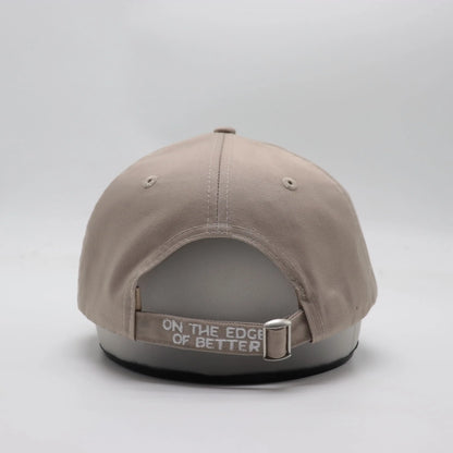 Backside view of The TideTurner hat in ivory color made of 65% recycled ocean bound plastic featuring embroidered Liminal Life's slogan  "On The Edge Of Better". 